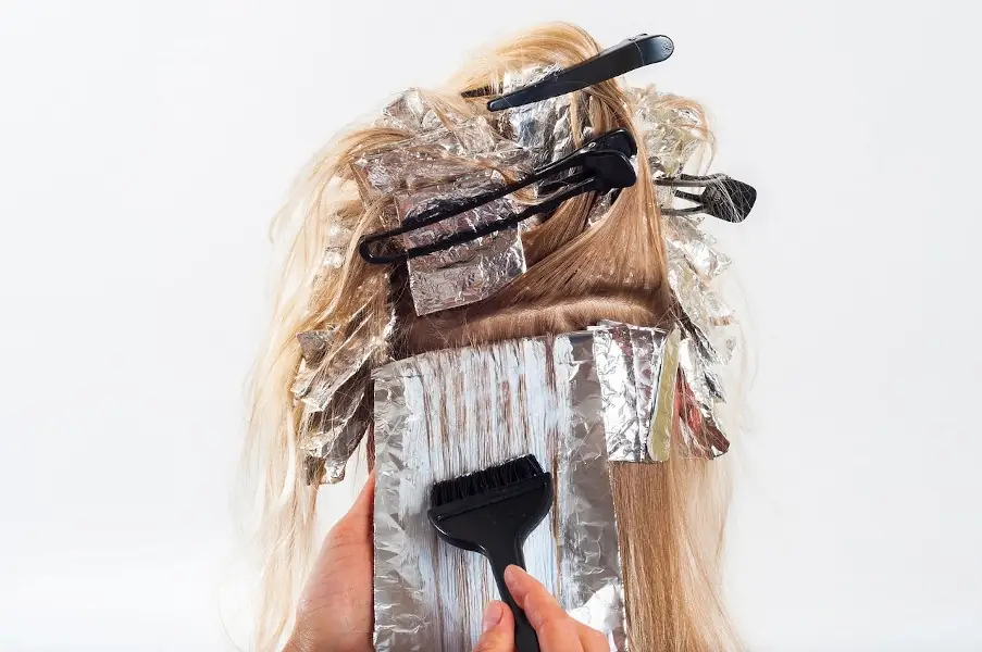 Peluquera tiñiendo a un cliente
